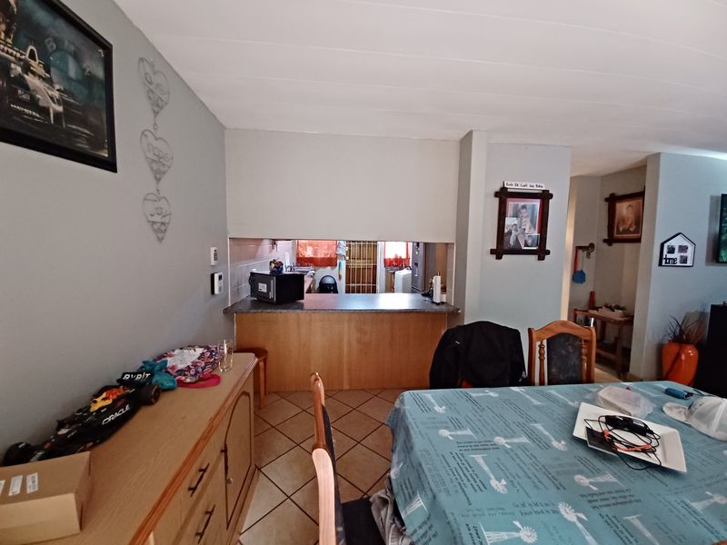Open plan living and dining area featuring a breakfast bar pass-through to the kitchen and tiled flooring throughout.