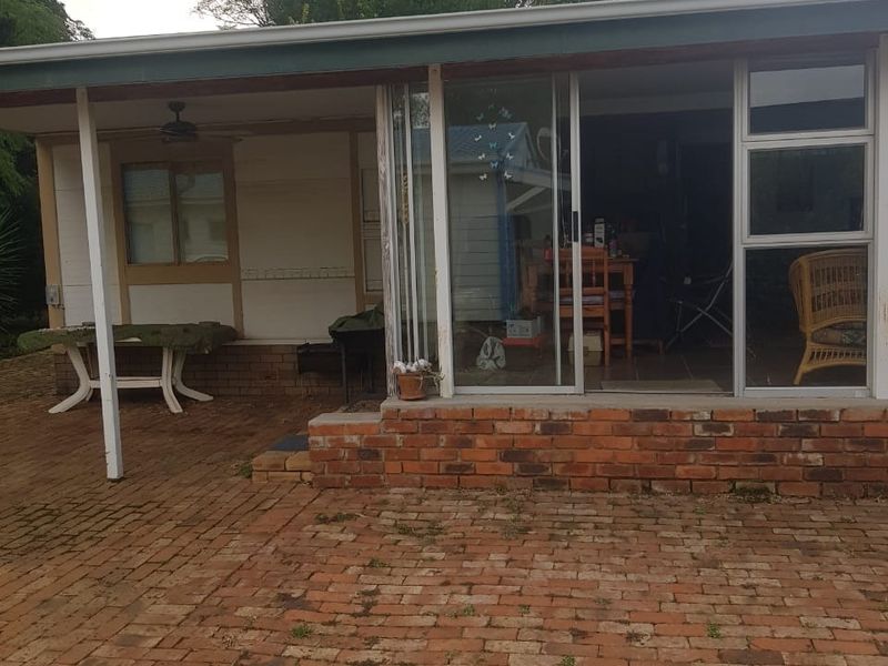 A covered patio area featuring brick paving, a brick base, and sliding glass doors leading into the interior living space.