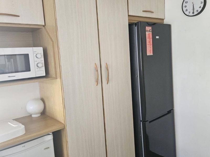 A functional kitchen area featuring light wood-tone built-in cabinetry, laminate countertops, and dedicated space for integrated appliances.