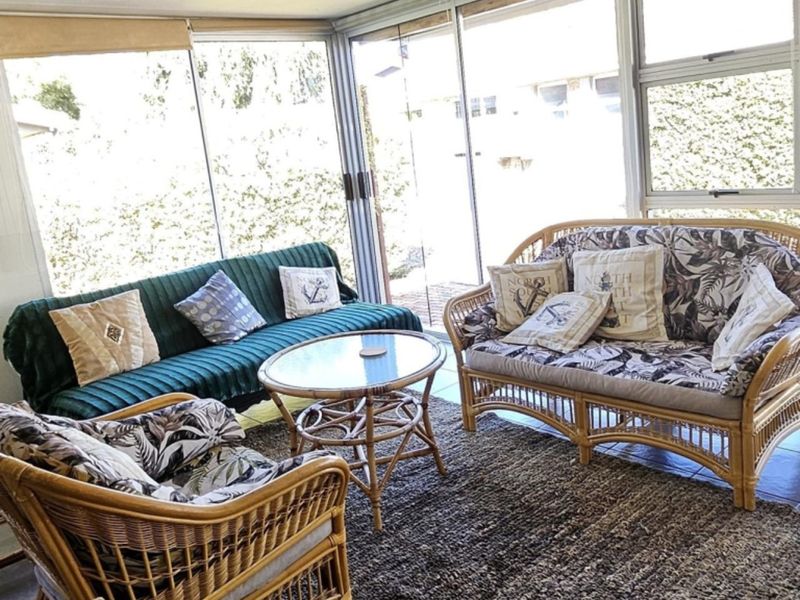 A sun-drenched enclosed patio featuring large sliding glass doors and tiled flooring, offering a bright and versatile space for relaxation.