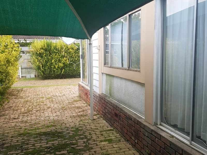 Outdoor patio area featuring brick paving and sliding glass door access, currently requiring maintenance due to moss and algae accumulation.