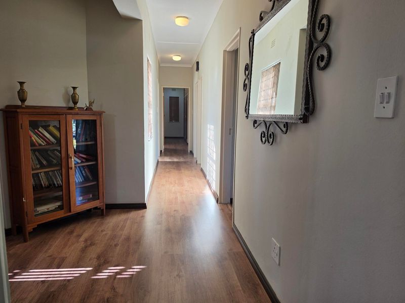 A well-lit hallway featuring laminate wood flooring and neutral wall finishes, providing access to multiple rooms within the home.