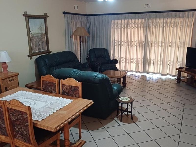 Spacious living area featuring tiled flooring and large sliding glass doors with security gates, providing access to the outdoor space.