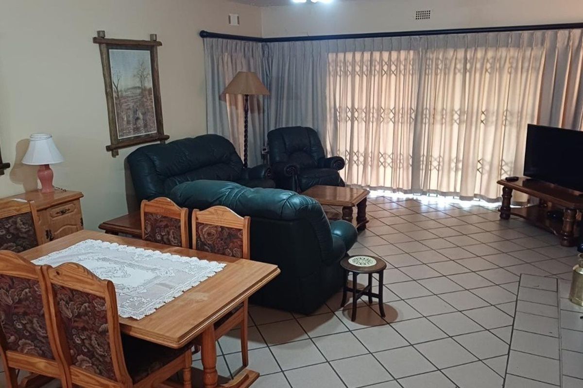 Spacious living area featuring tiled flooring and large sliding glass doors with security gates, providing access to the outdoor space.