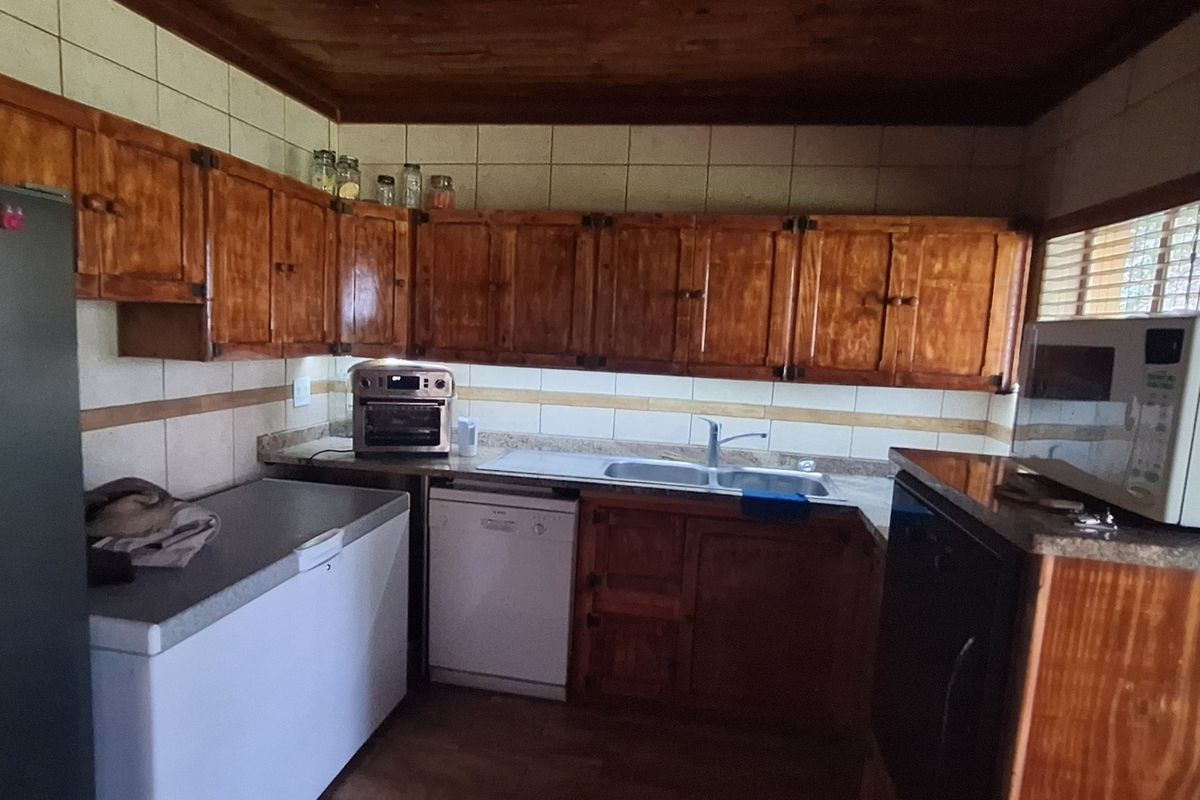 A functional kitchen featuring extensive wooden cabinetry, a double basin sink, tiled backsplash, and a warm wooden ceiling finish.