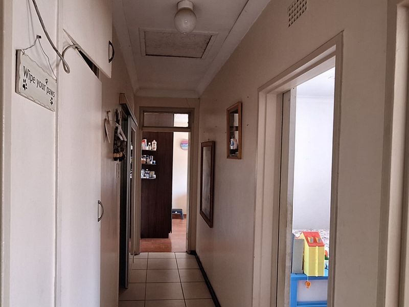 A functional hallway featuring tiled flooring, built-in storage cupboards, and access to adjacent rooms, providing a central circulation space within the home.