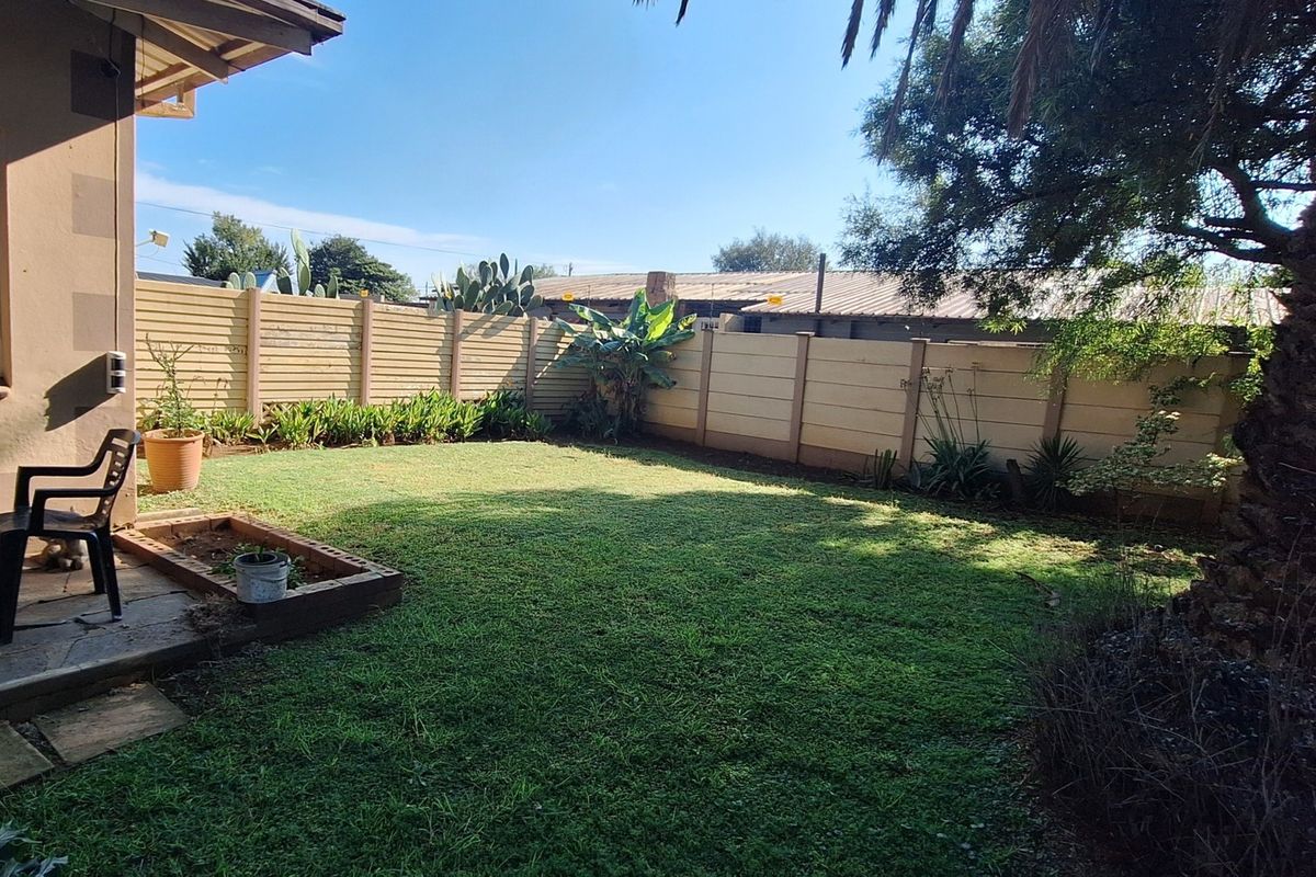 A private rear garden featuring a lawn, a paved patio area, and secure precast concrete boundary walls.