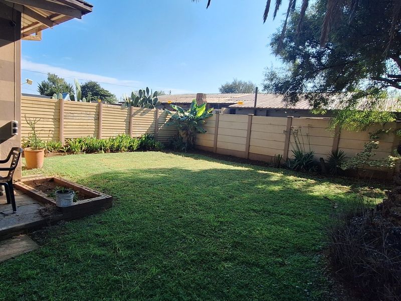 A private rear garden featuring a lawn, a paved patio area, and secure precast concrete boundary walls.