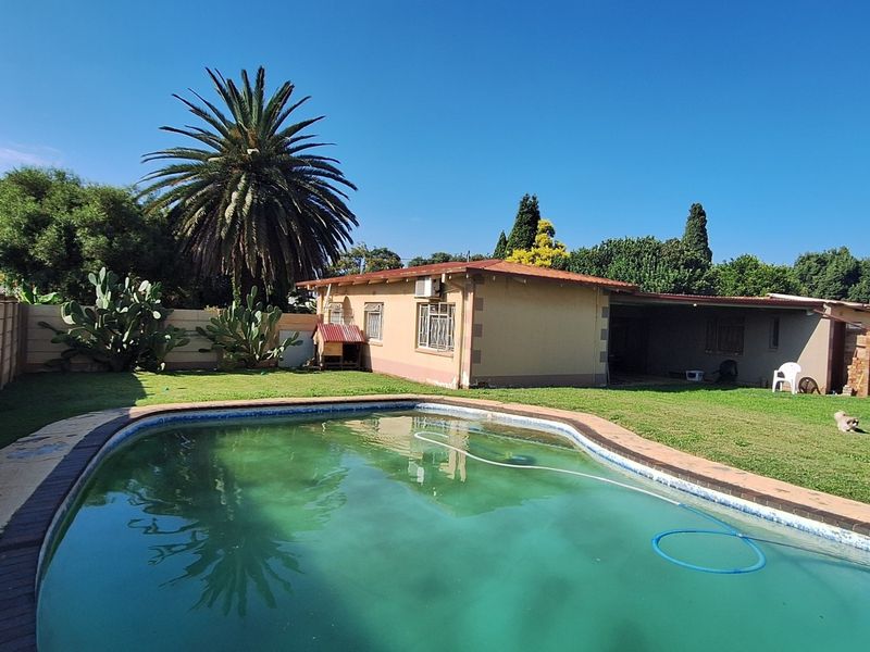 Rear garden area featuring a swimming pool, covered patio, and perimeter boundary walling.