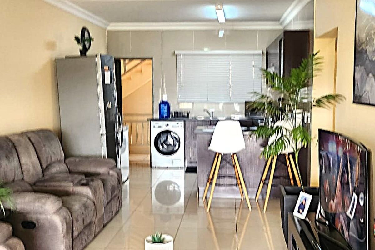Open-plan living area featuring tiled flooring and a functional kitchen space with built-in cabinetry and countertops, creating a cohesive and practical living environment.