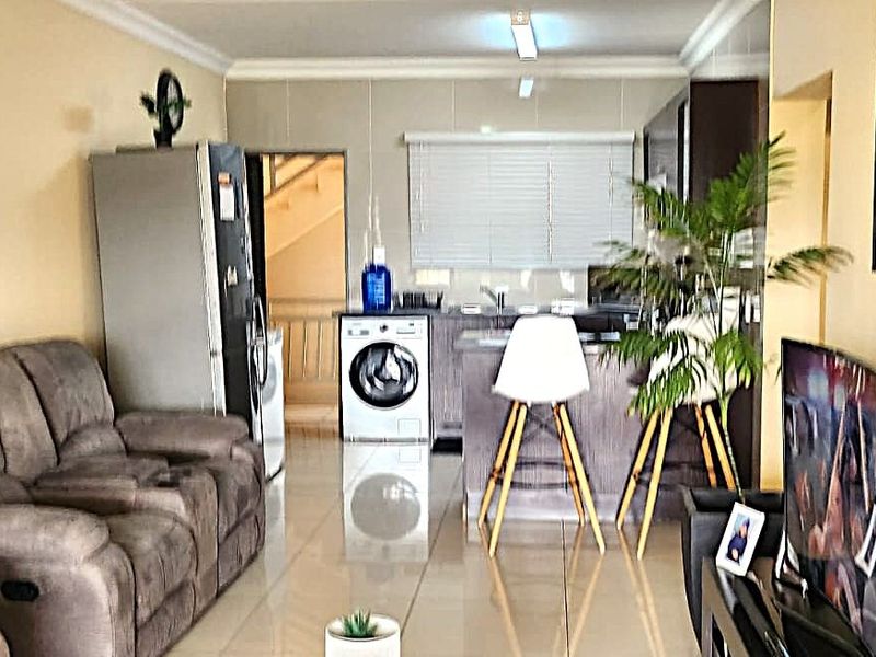 Open-plan living area featuring tiled flooring and a functional kitchen space with built-in cabinetry and countertops, creating a cohesive and practical living environment.