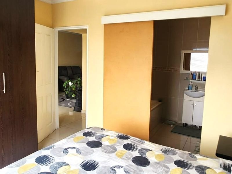 Bedroom featuring a large built-in wardrobe and direct access to an en-suite bathroom with tiled flooring.