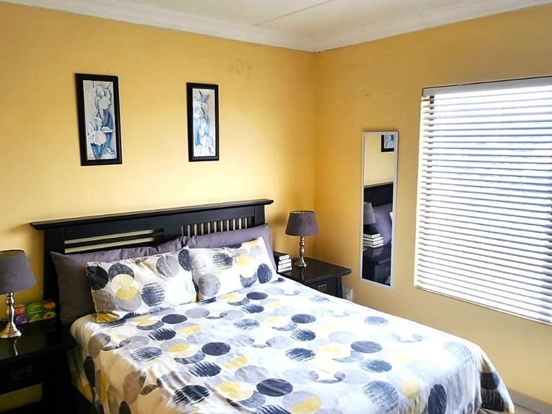 A cozy bedroom featuring yellow walls, a window with venetian blinds, and built-in storage space.