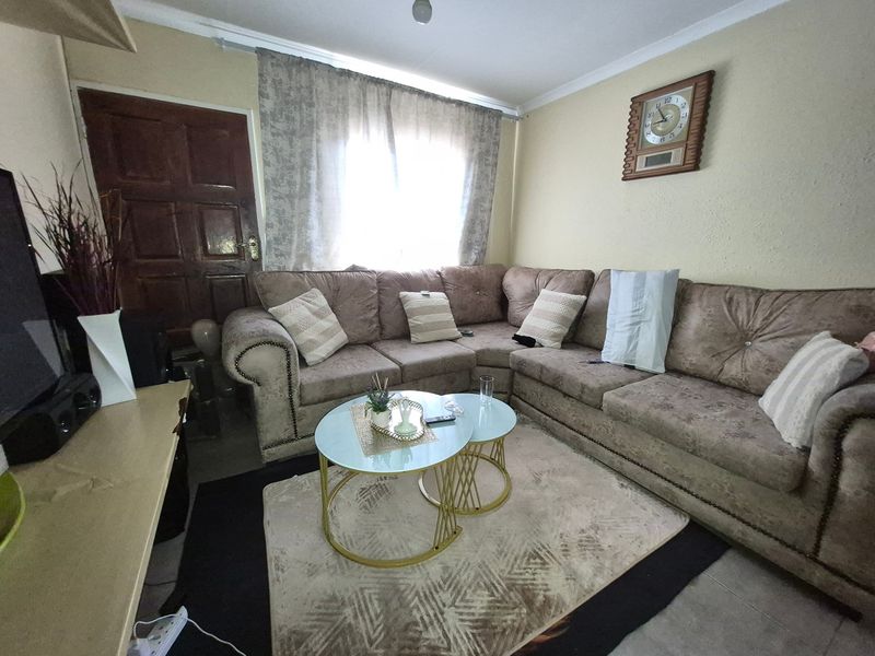 A cozy living room featuring tiled flooring, a timber entrance door, and coved ceiling cornicing, providing a functional and comfortable living space.