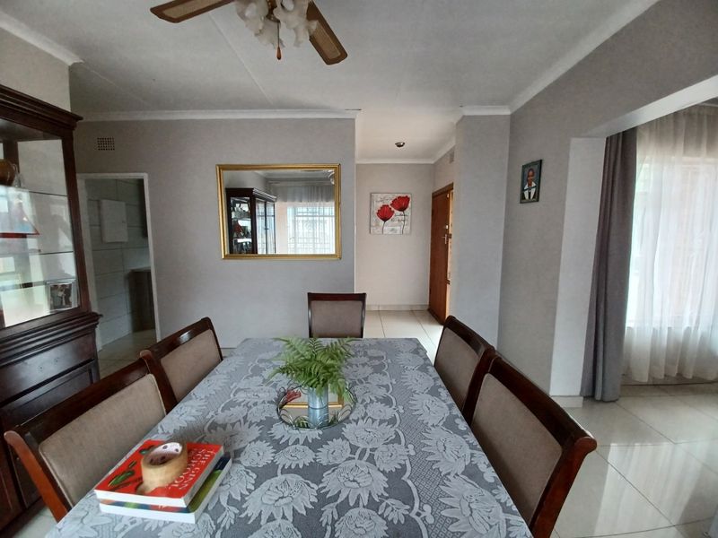 A functional dining room featuring tiled flooring and a ceiling fan, providing a central space for family meals and gatherings.