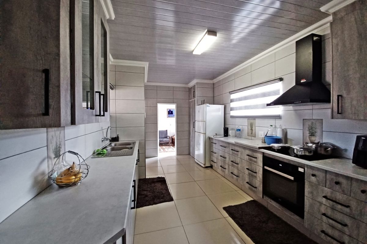 Modern kitchen featuring extensive built-in cabinetry, tiled finishes, integrated oven and hob, and a sleek extractor fan, offering a functional and well-maintained workspace.