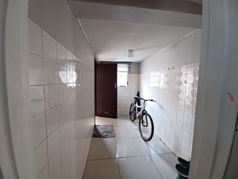 A functional utility space featuring full-height ceramic wall tiling and tiled flooring, providing a clean and durable area for household tasks.