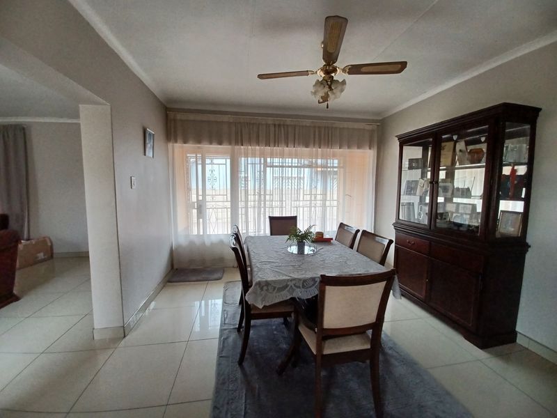 A dining room featuring tiled flooring, a ceiling fan, and a sliding door with security gate leading to the exterior.