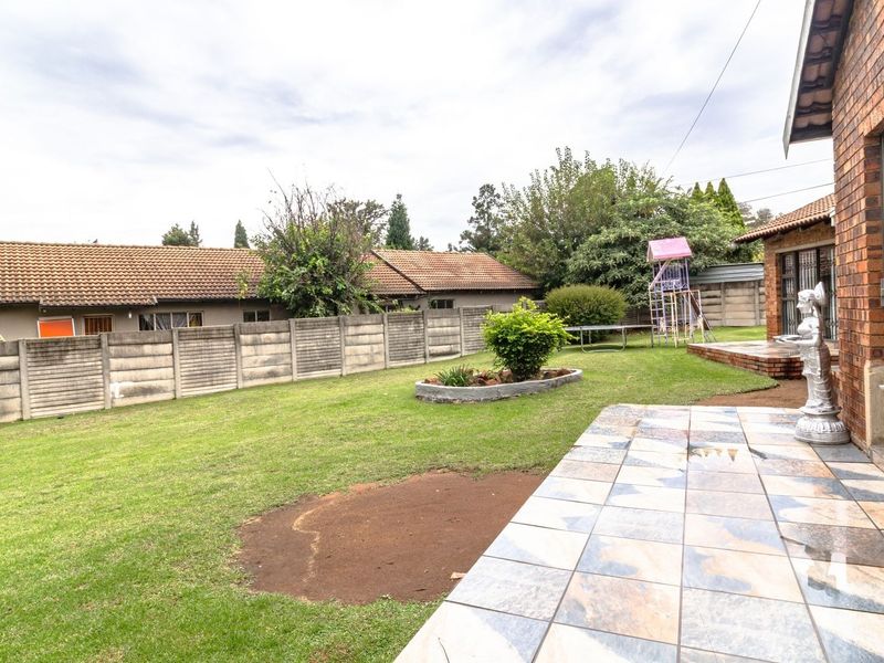 Rear garden area featuring a tiled patio, brick exterior wall, and precast concrete boundary fencing.