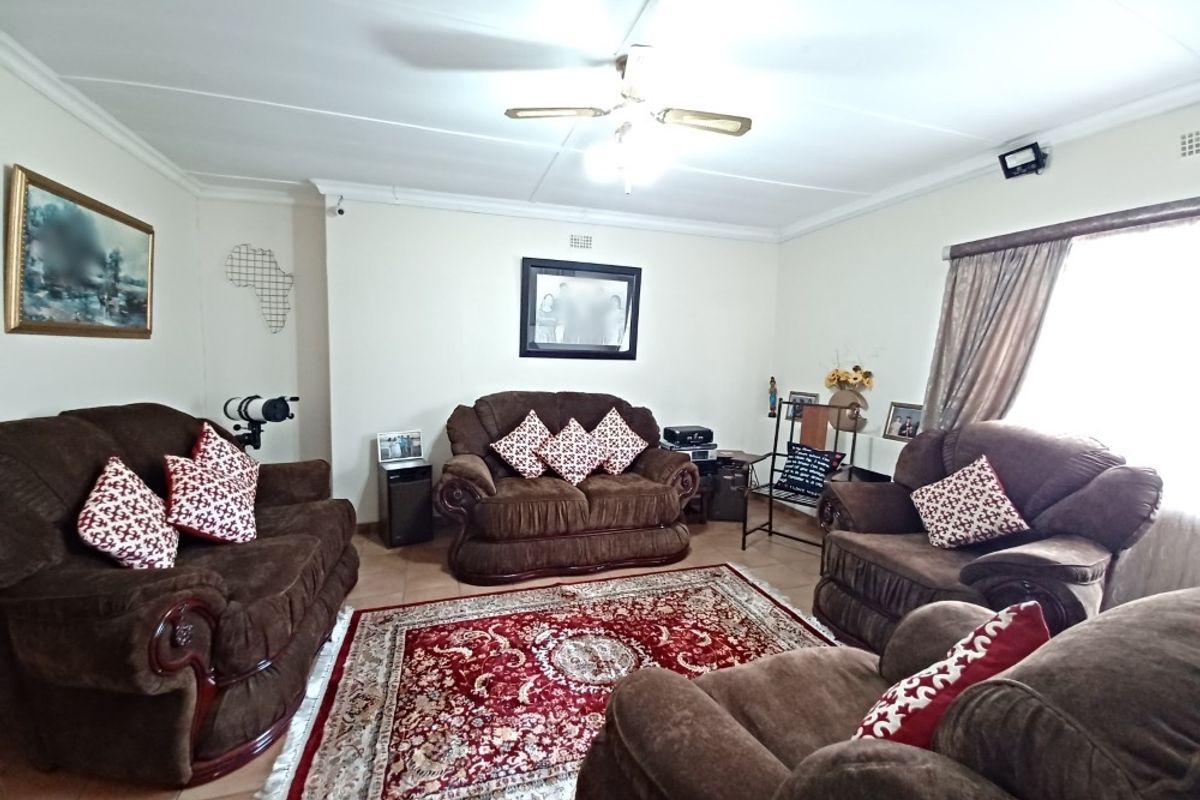 A spacious living room featuring tiled flooring, coved cornicing, and a central ceiling fan, providing a comfortable and functional family living area.