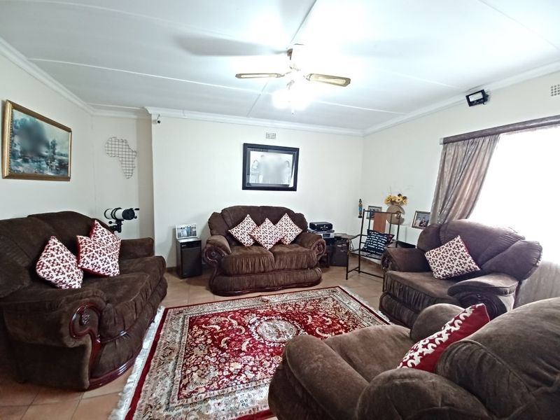 A spacious living room featuring tiled flooring, coved cornicing, and a central ceiling fan, providing a comfortable and functional family living area.
