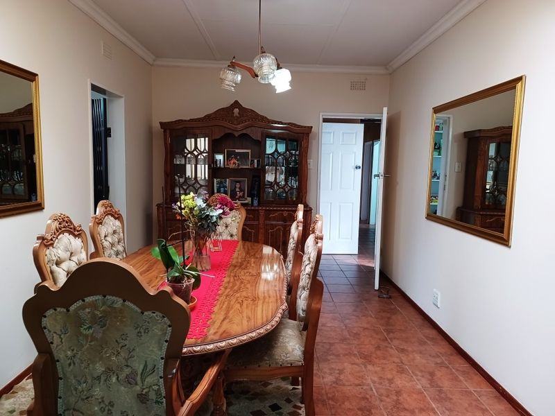 A traditional dining room featuring tiled flooring, ceiling cornice, and a central pendant light fixture, providing a functional space for formal meals.