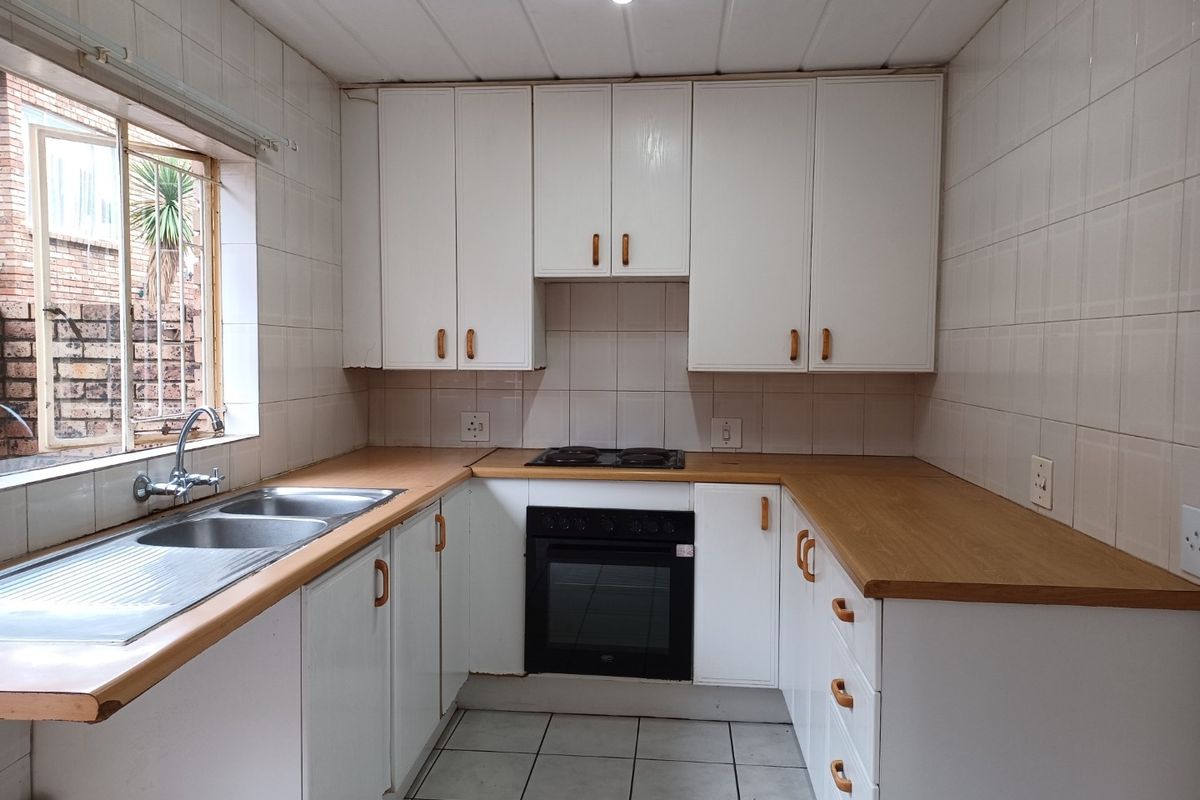 A functional kitchen featuring white cabinetry, laminate countertops, a built-in oven, and a double stainless steel sink with tiled splashbacks.