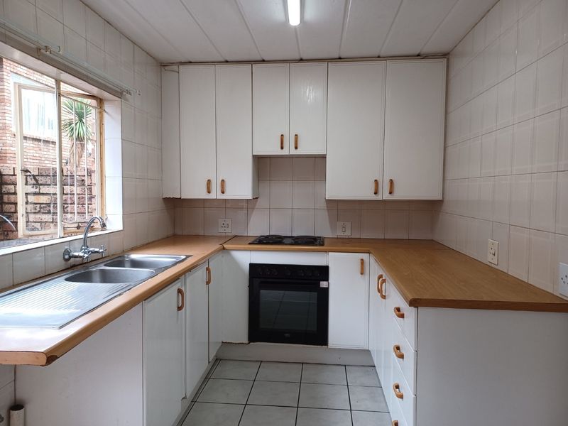 A functional kitchen featuring white cabinetry, laminate countertops, a built-in oven, and a double stainless steel sink with tiled splashbacks.