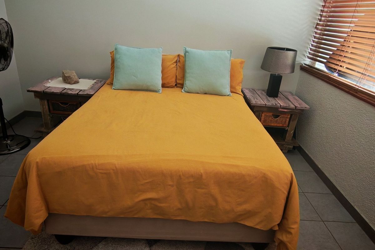 A bedroom featuring tiled flooring and wooden venetian blinds, providing a functional space with neutral wall finishes.
