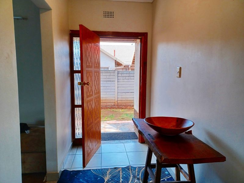 A bright entrance area featuring tiled flooring and a solid wood door leading to an outdoor space.