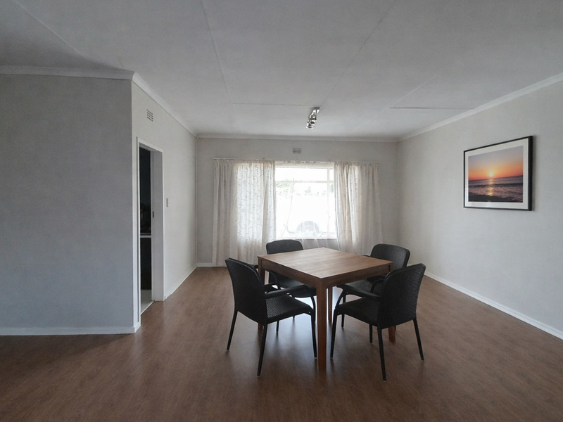 A bright and spacious dining room featuring modern laminate flooring, neutral walls, and a coved ceiling, providing a clean and versatile living space.