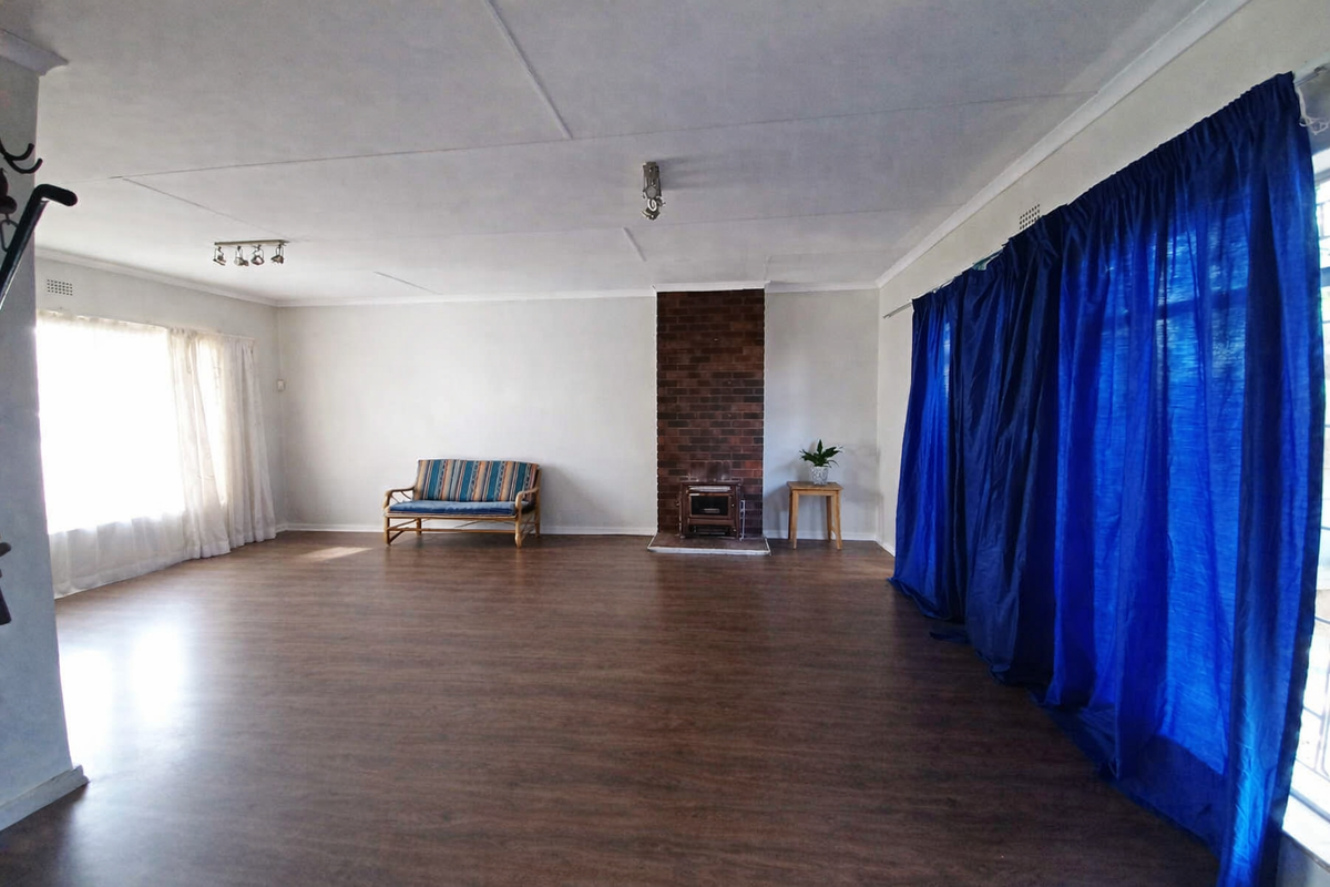 Spacious living room featuring wood-look laminate flooring, a central brick fireplace, and ample natural light from large windows.
