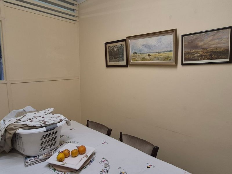 A dining area featuring neutral walls and an internal window with louvre detailing, providing a functional space for meals.