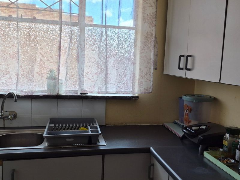 A functional kitchen area featuring double stainless steel sinks, laminate countertops, and ample upper and lower cabinetry with a tiled splashback.