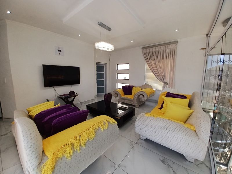 A bright living room featuring polished tiled flooring, recessed ceiling lighting, and a large sliding glass door providing access to the exterior.