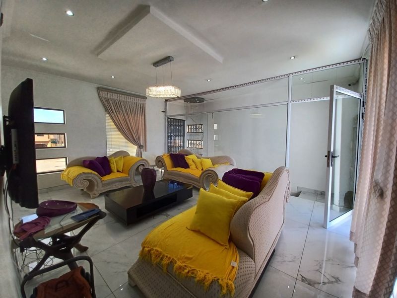 Spacious living room featuring tiled flooring, recessed ceiling lighting, and a modern glass partition wall creating a distinct architectural separation.