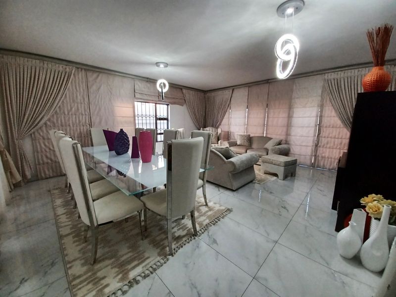 Spacious open-plan living and dining area featuring polished marble-look floor tiles and contemporary pendant lighting.