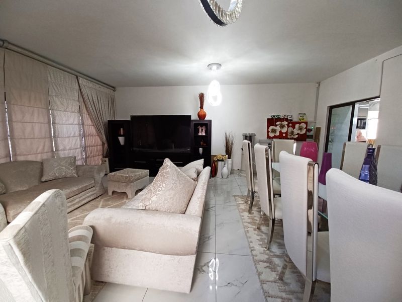 Spacious open-plan living and dining area featuring polished porcelain floor tiles and modern recessed ceiling lighting.