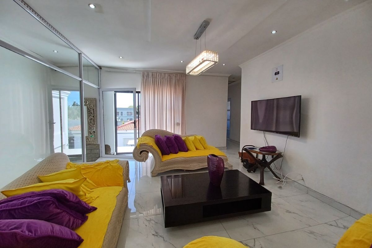 A bright living room featuring marble-look floor tiles, recessed downlighting, a modern pendant fixture, and a sliding glass door leading to the exterior.