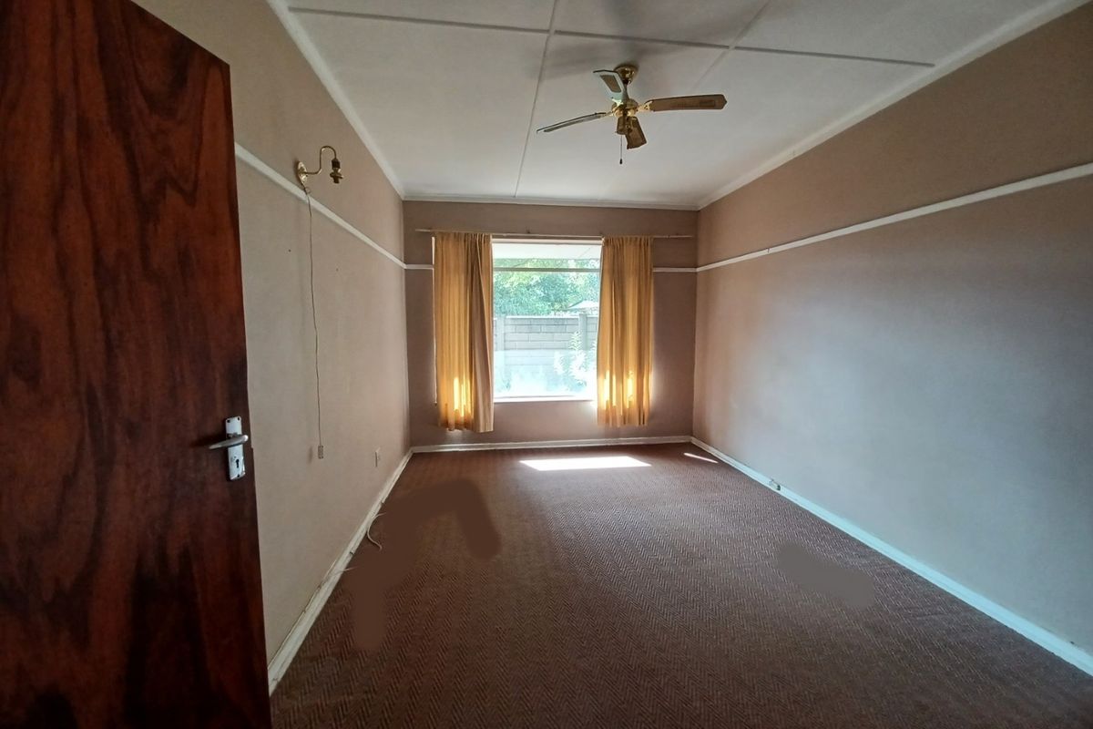 An empty bedroom featuring a ceiling fan, picture rails, and carpeted flooring, offering a blank canvas for renovation and interior design updates.