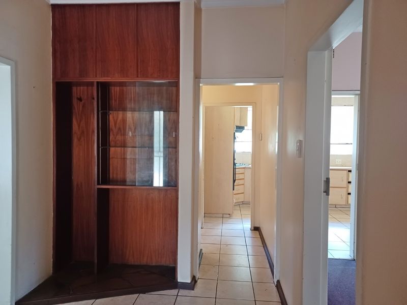 A functional hallway featuring built-in wooden cabinetry and ceramic tile flooring, providing access to adjacent rooms within the home.