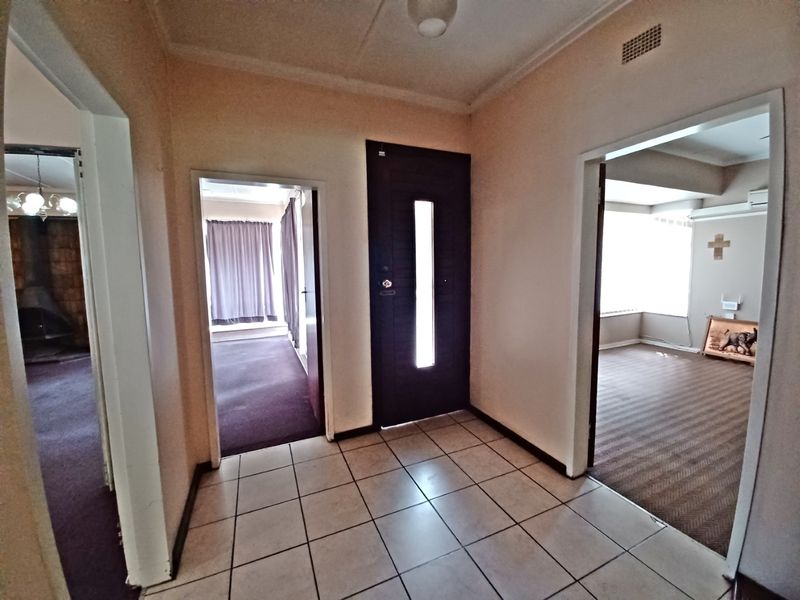 A bright entrance hall featuring tiled flooring and a modern front door, providing access to multiple living areas within the home.