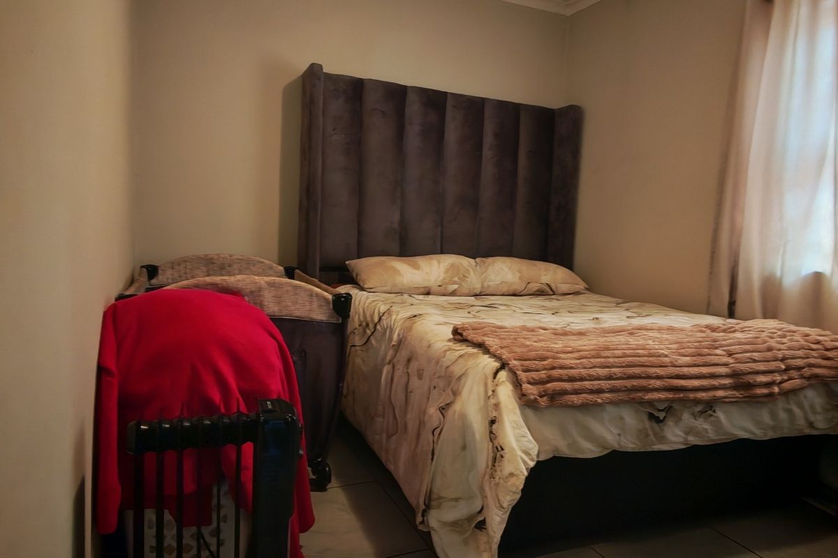 A compact bedroom featuring tiled flooring and neutral wall finishes, providing a functional space for rest.