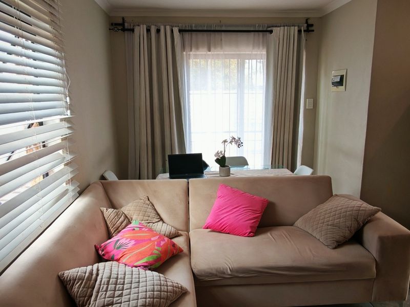 A cozy living area featuring tiled flooring, window blinds, and curtain rods, providing a functional space with natural light.