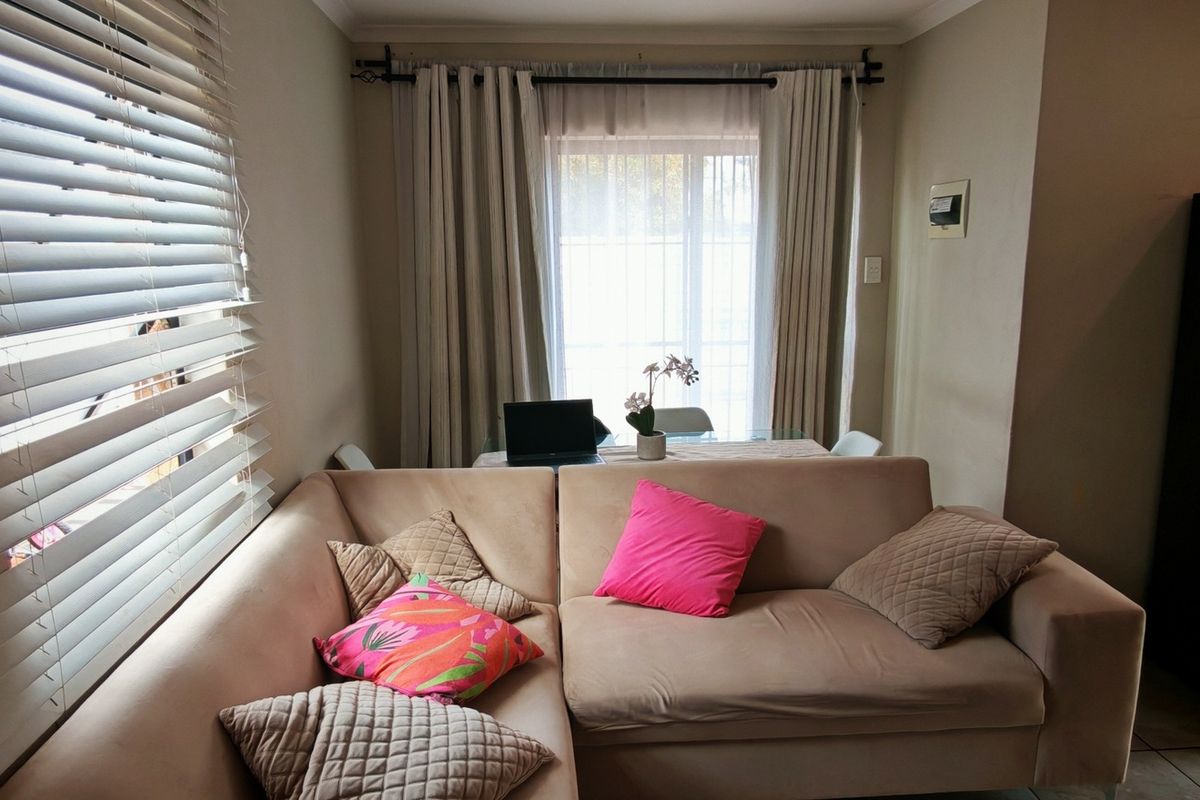 A cozy living area featuring tiled flooring, window blinds, and curtain rods, providing a functional space with natural light.