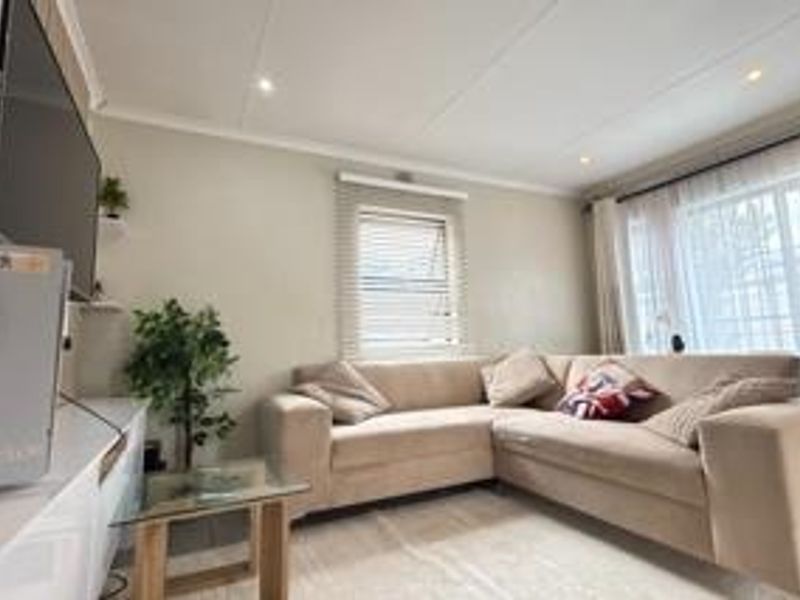 A comfortable living room featuring recessed downlighting, venetian blinds, and a sliding glass door providing natural light.