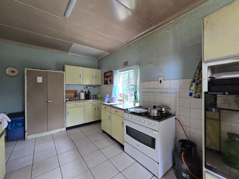 A dated kitchen featuring original cabinetry, tiled flooring, and a gas stove, offering significant potential for modernization and renovation.