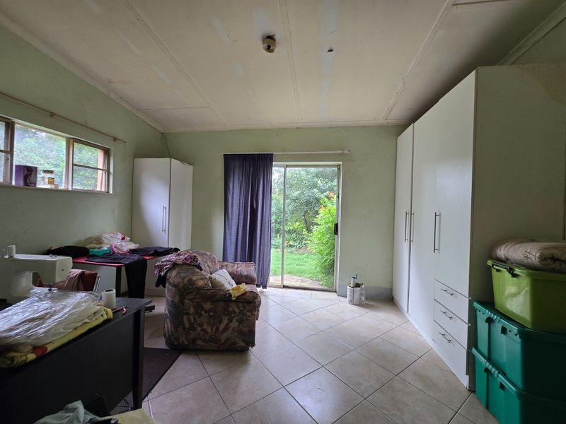 Bedroom featuring built-in cupboards, tiled flooring, and a sliding glass door providing direct access to the garden.