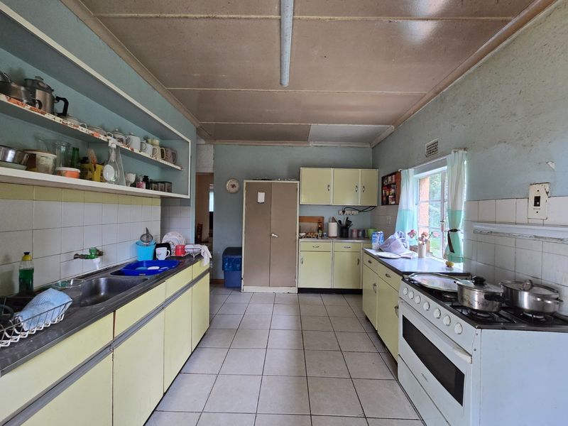 A dated kitchen featuring original cabinetry, tiled flooring, and a freestanding stove, offering significant potential for modernization and renovation.