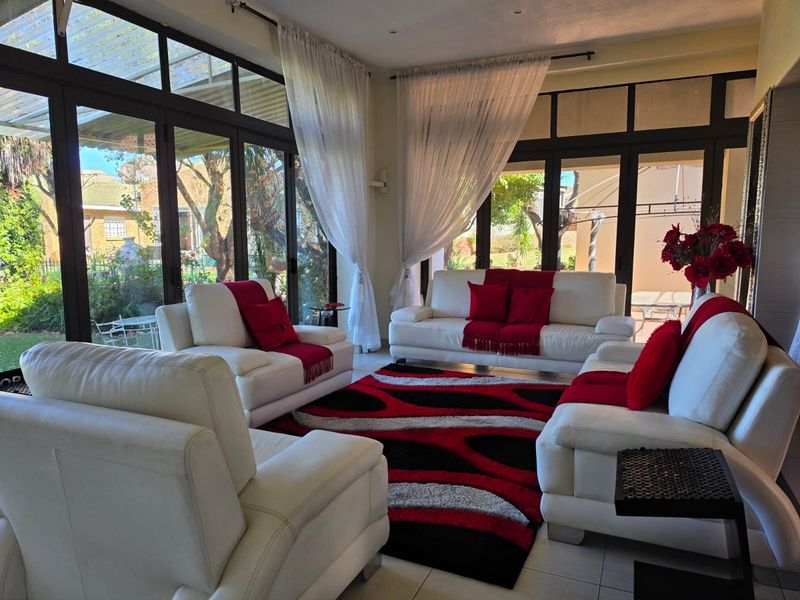 Bright living room featuring extensive floor-to-ceiling glass sliding doors that provide abundant natural light and seamless access to the outdoor garden area.